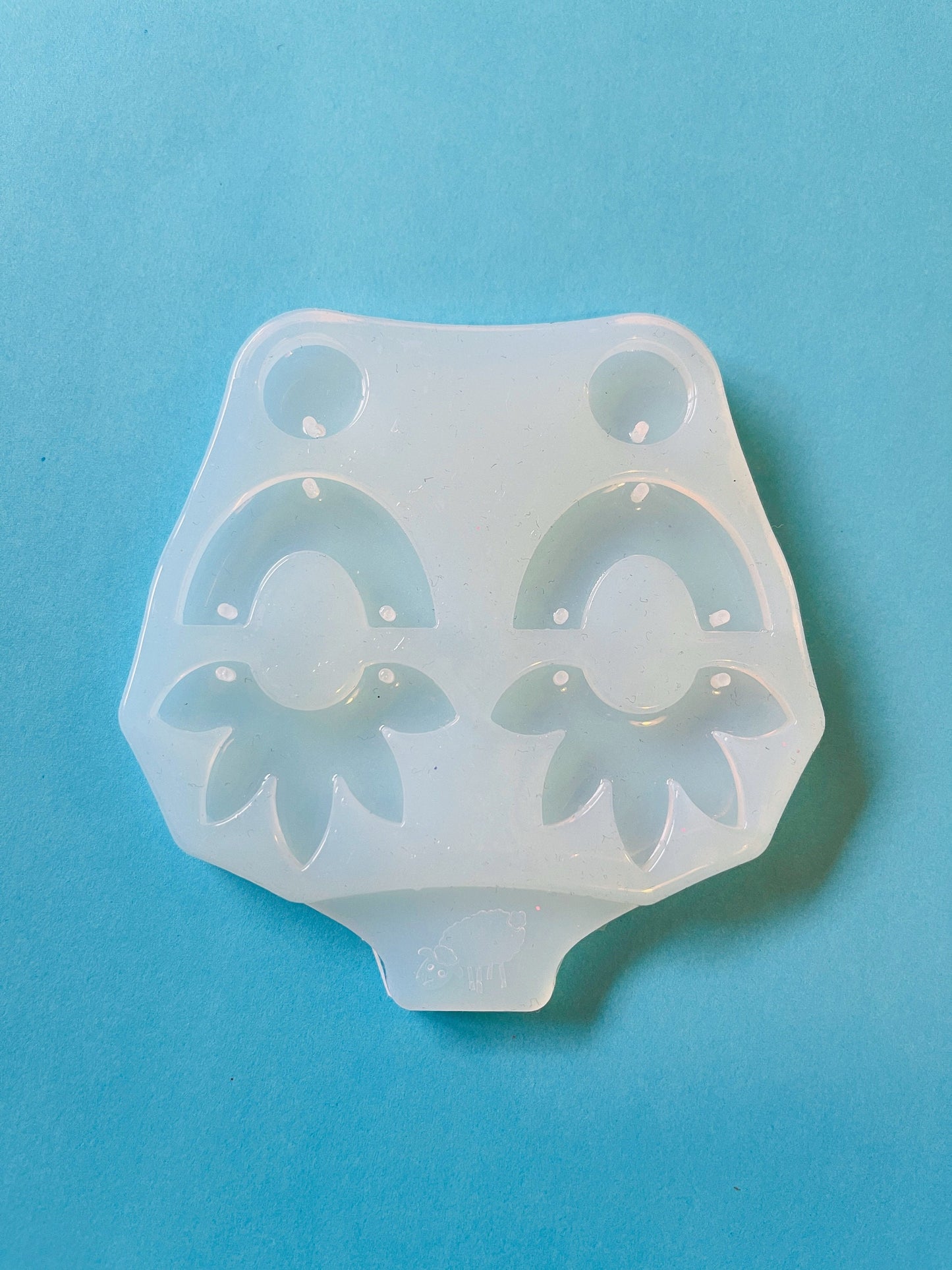 Form for epoxy. A set of earrings in the form of an arc and a flower Silicone mold. Jewelry pendant from a casting mold. Glossy resin mold.